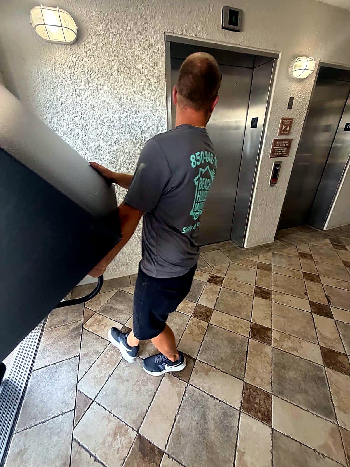Beach House Moving crew guiding a refrigerator to the sixth-floor elevator at a Destin resort