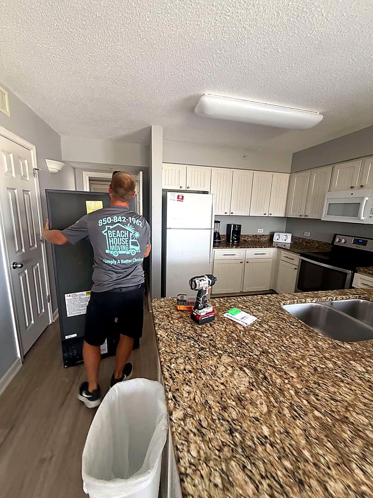 Beach House Moving crew positioning a refrigerator into a condo kitchen alcove in Destin