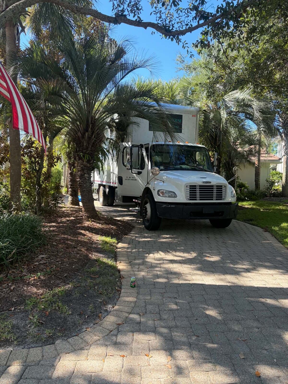 Beach House Moving box truck parked on a paver driveway at a Regatta Bay home in Destin, FL