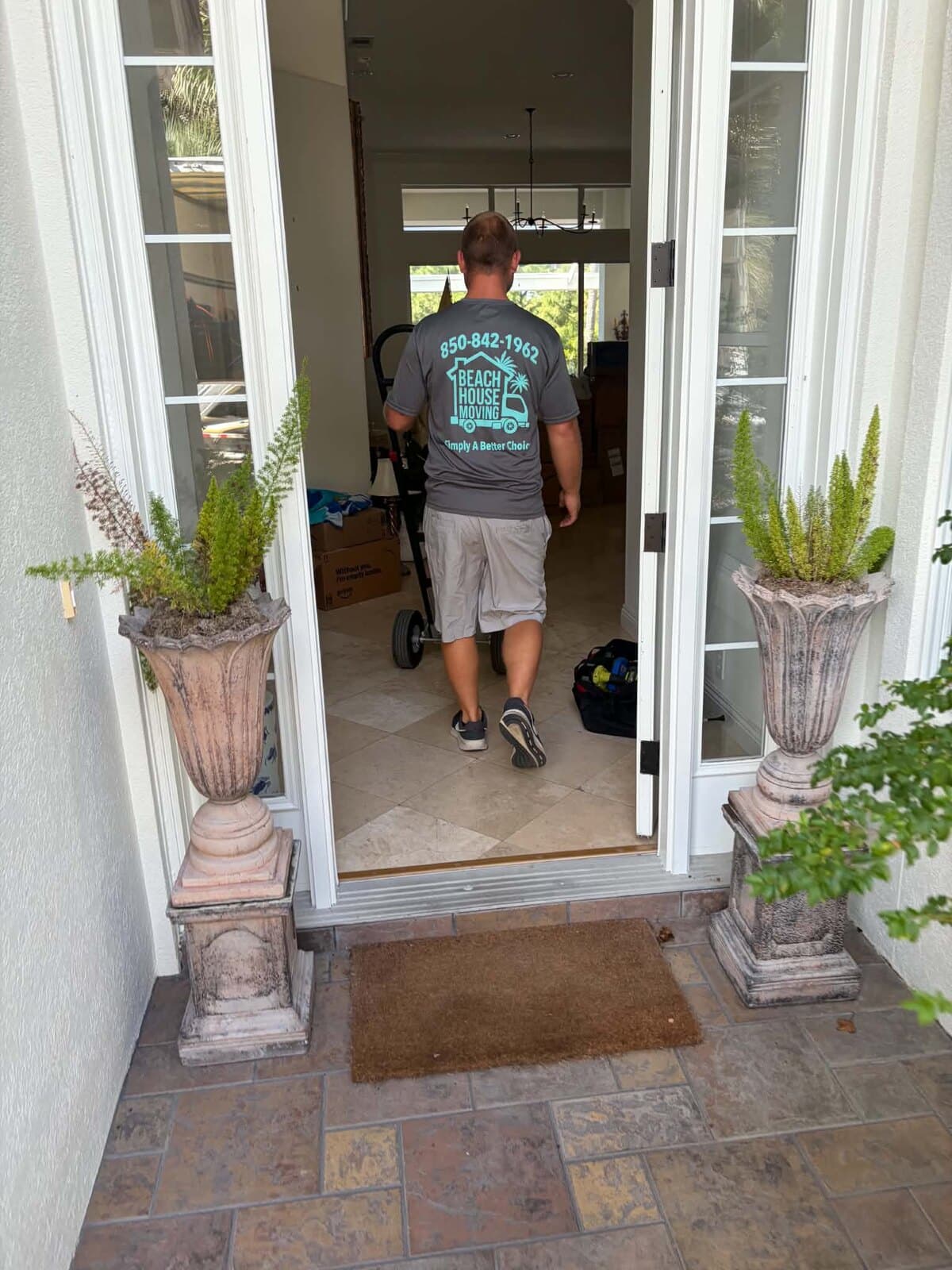 Beach House Moving crew member heading through open double front doors with a hand truck, Regatta Bay, Destin