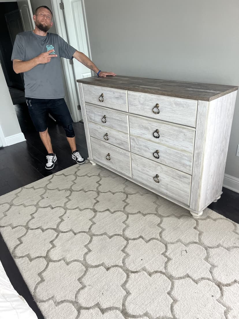 Beach House Moving crew member Les with a whitewashed coastal dresser placed and leveled in a Santa Rosa Beach bedroom