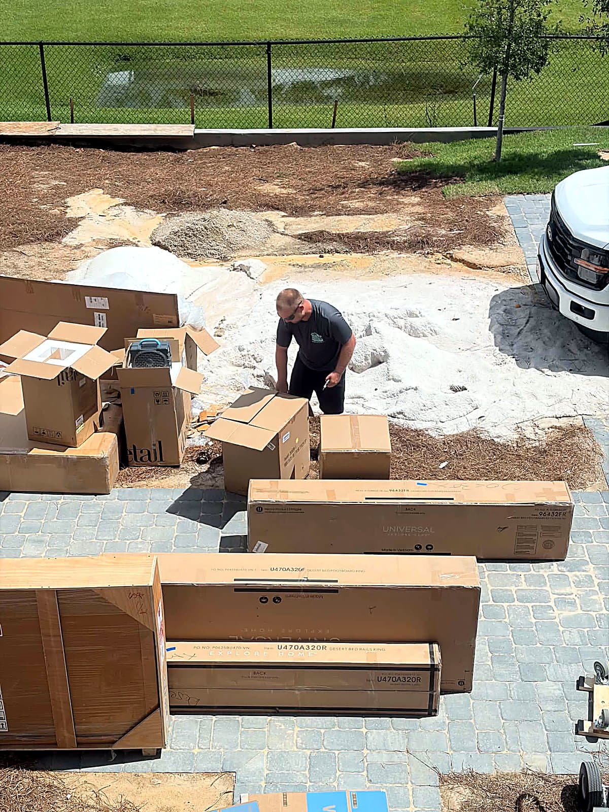 Movers uncrating a king bed set in the driveway before carrying it inside