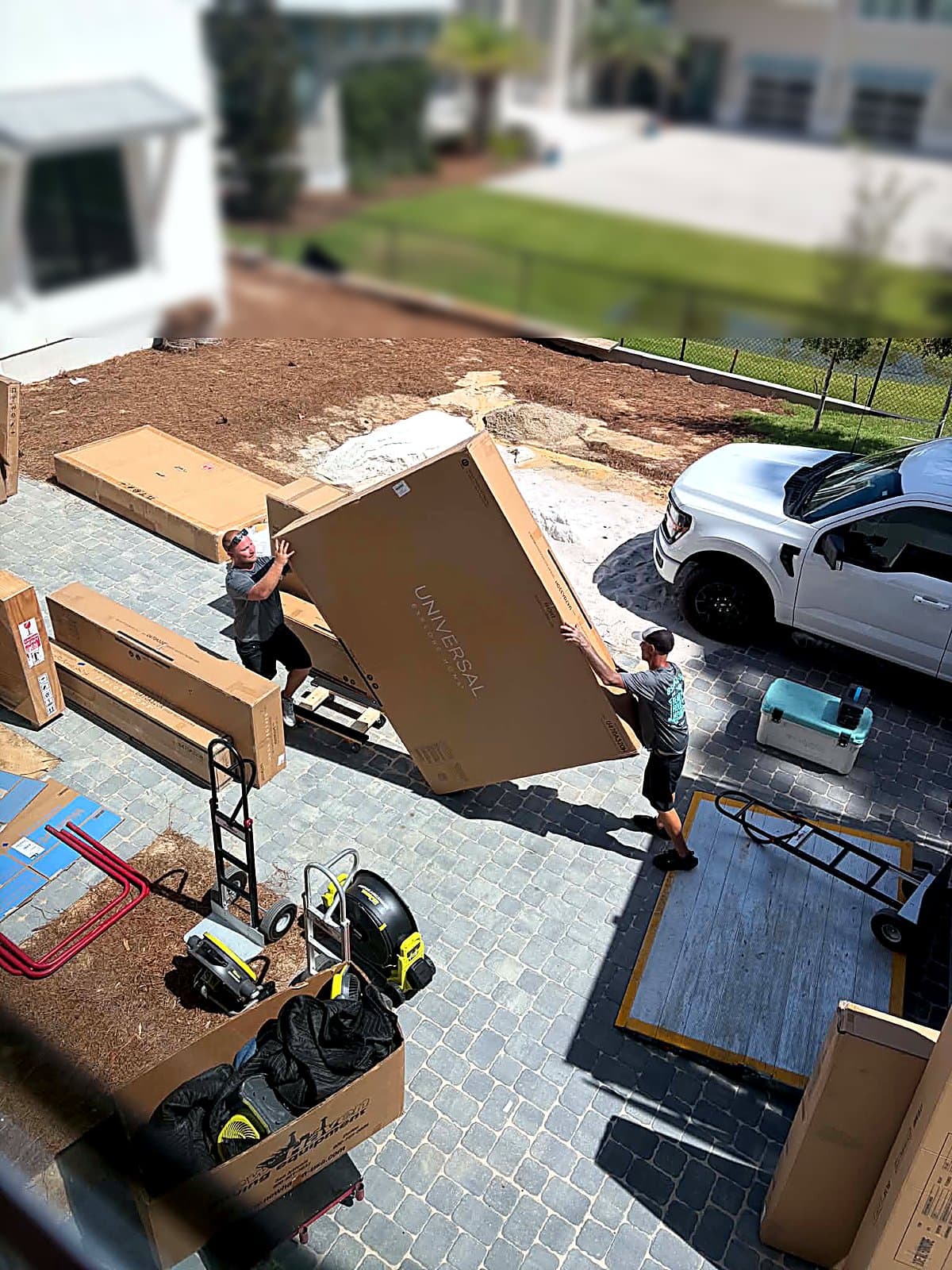 Two Beach House Moving crew carrying an oversized king headboard box