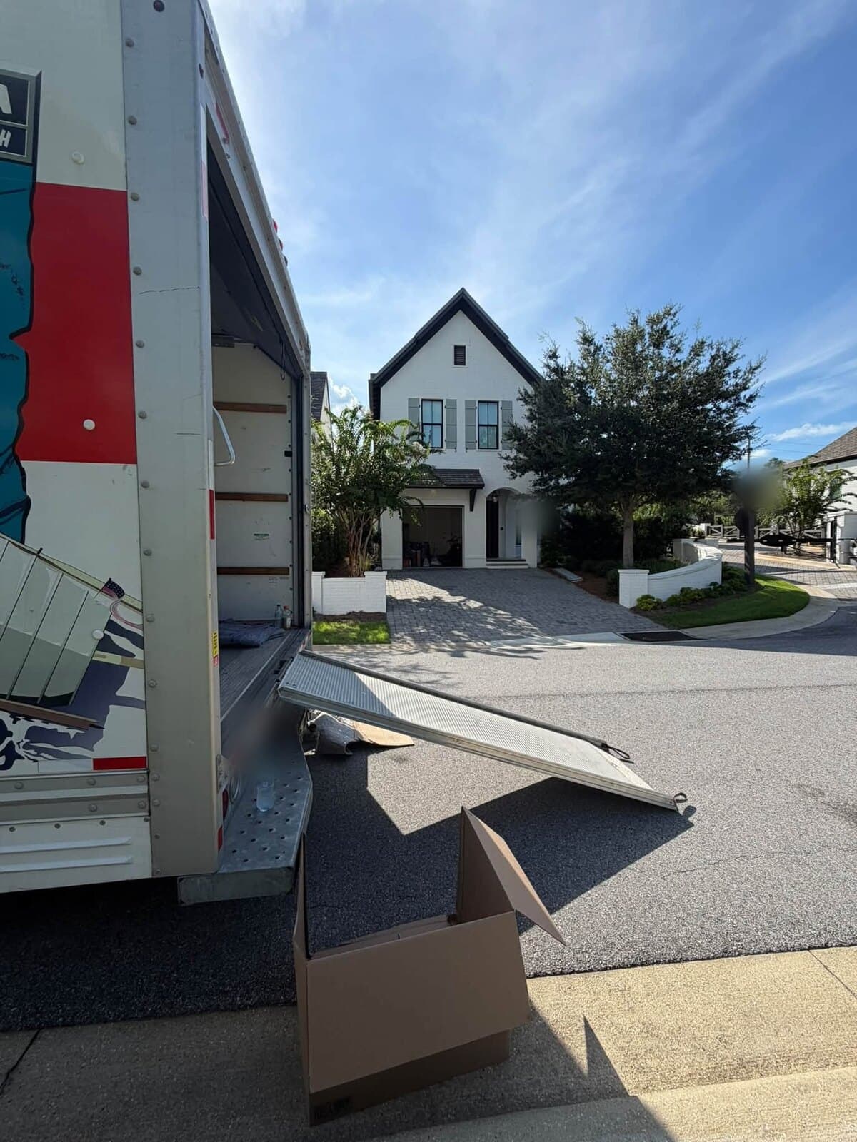 Moving truck with its ramp down in front of a white two-story home with a paver driveway on a cul-de-sac in Santa Rosa Beach, FL