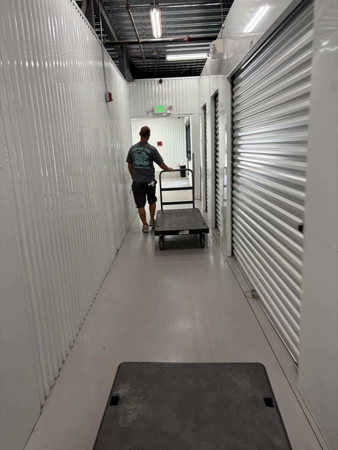 Beach House Moving mover wheeling a flat cart through a climate-controlled storage facility
