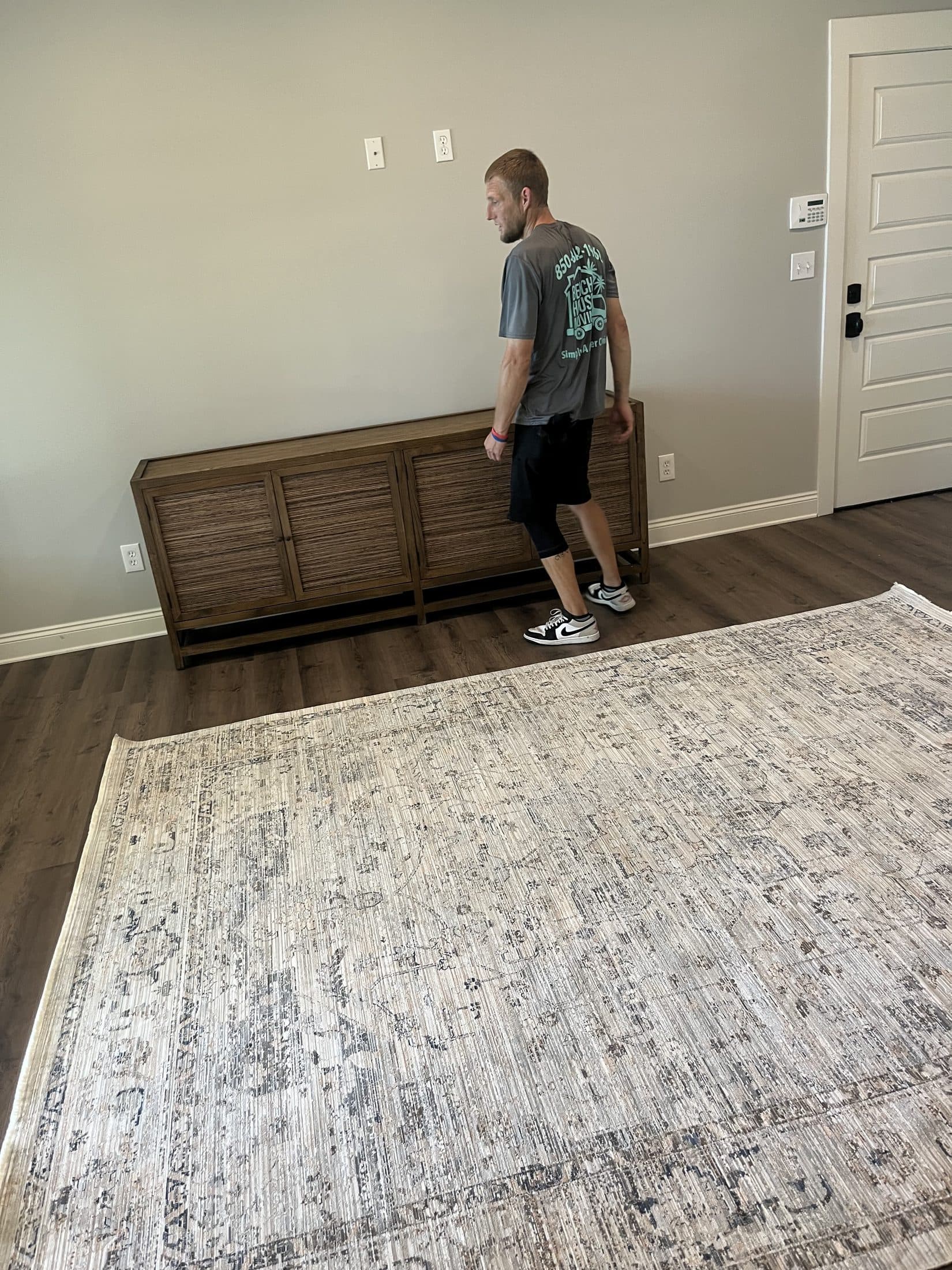 Beach House Moving branded crew member placing furniture and a designer rug during a luxury home move-in
