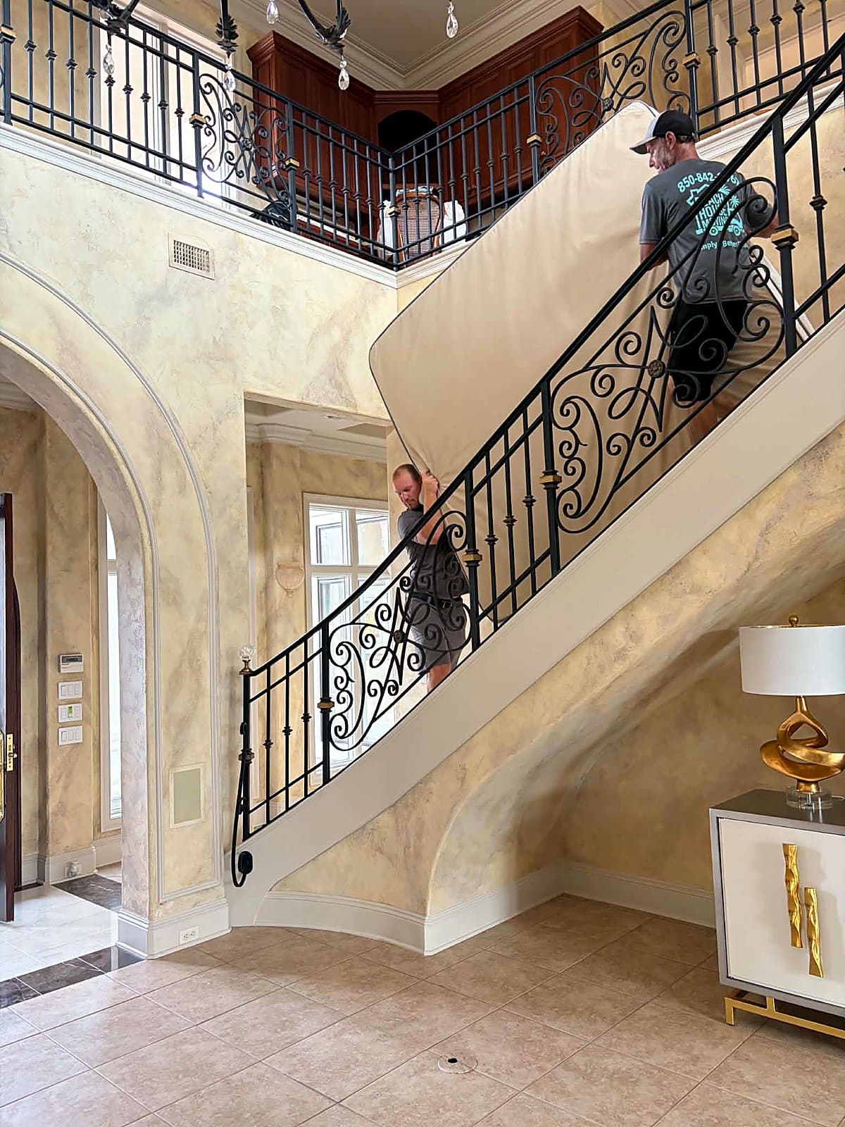 Beach House Moving crew carrying a mattress up a curved iron staircase