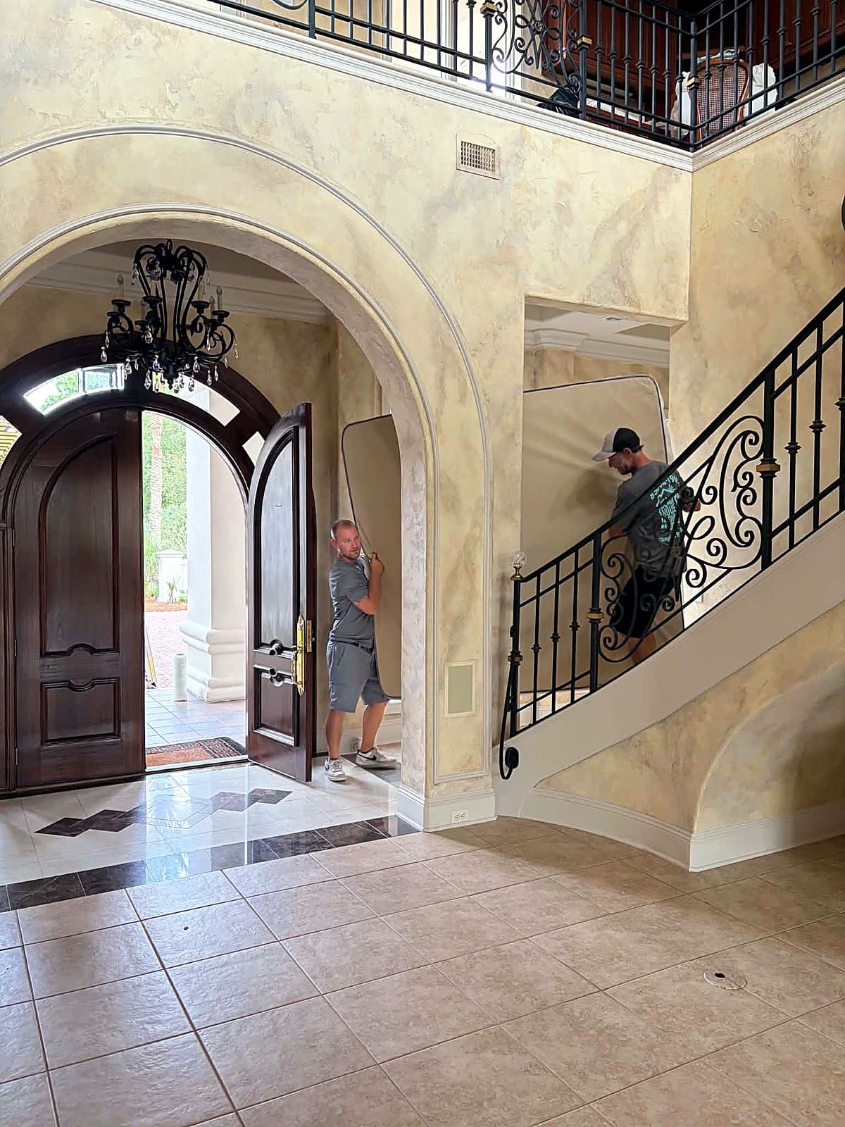 Beach House Moving crew carrying a mattress through a luxury Emerald Coast home foyer