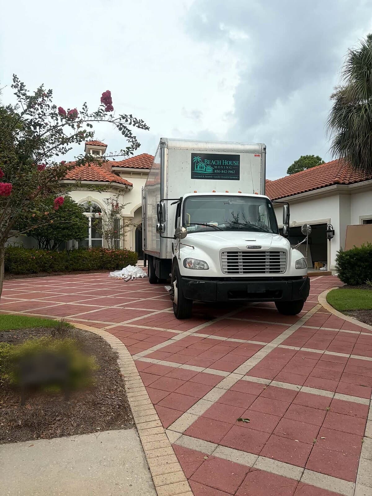Beach House Moving box truck staged on the paver driveway of a Burnt Pine home in Miramar Beach, FL for a furniture install