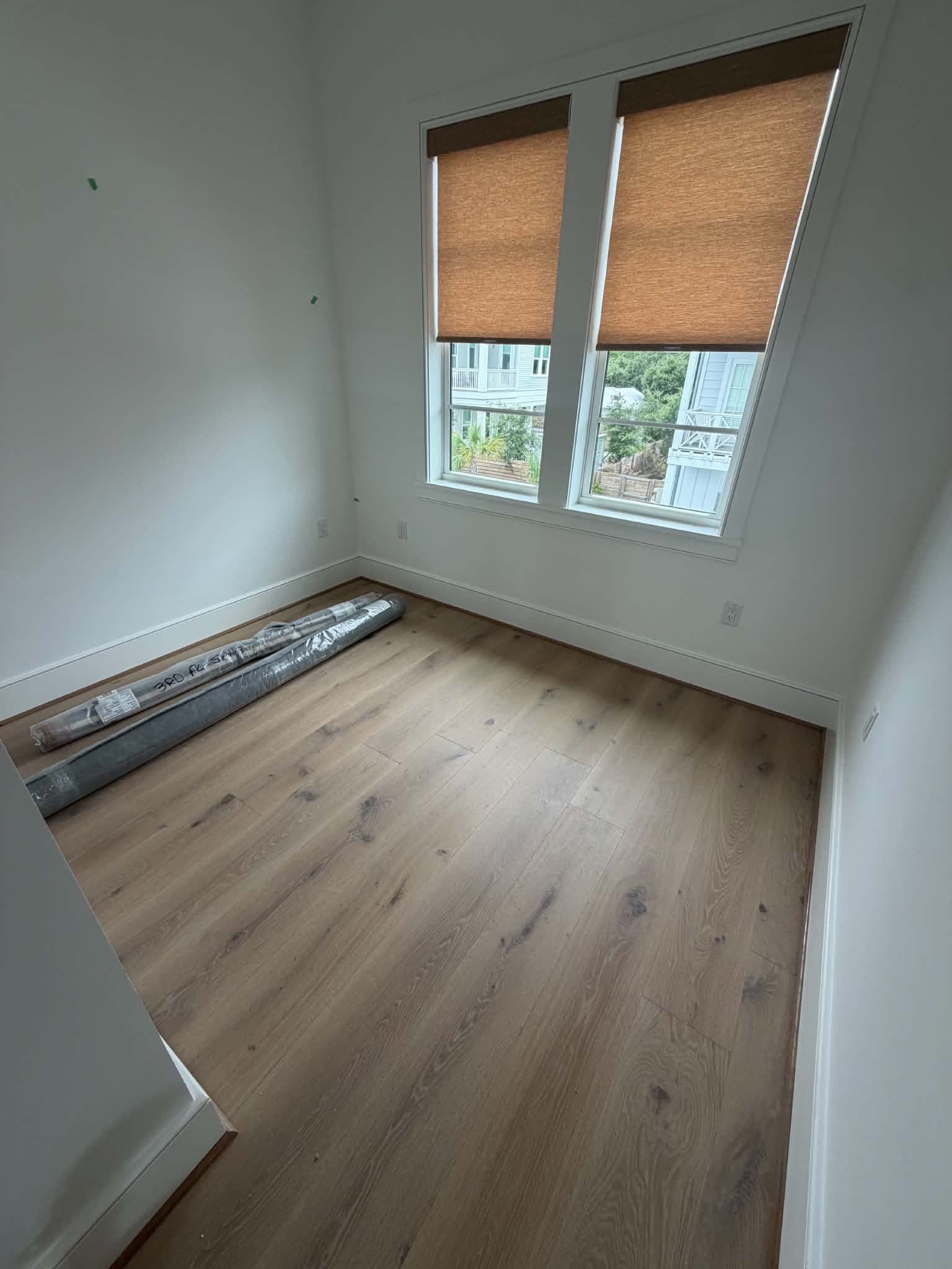 Wrapped rugs labeled by floor staged in an empty new-construction beach home on 30A by Beach House Moving