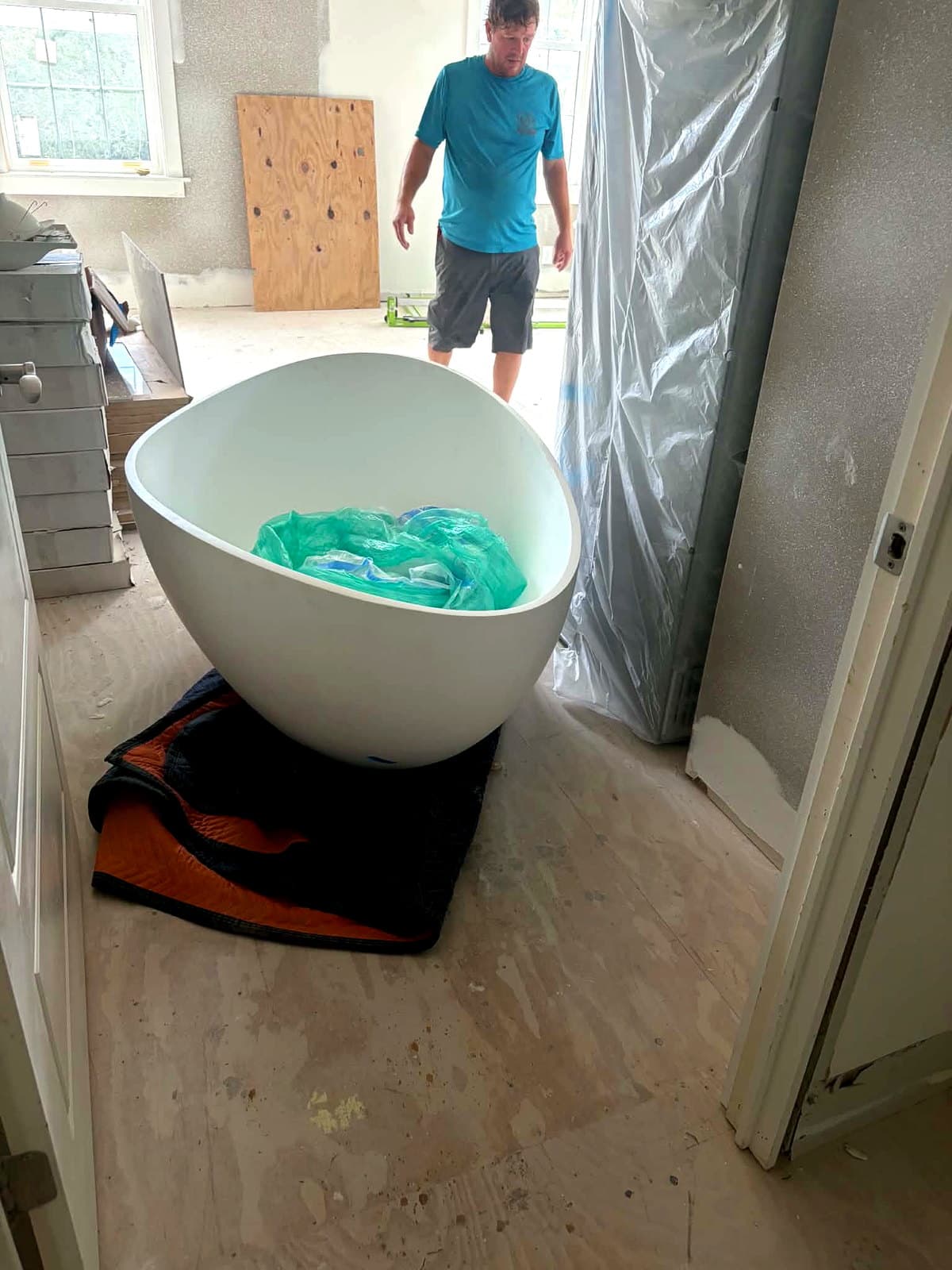 Beach House Moving mover Keith setting a freestanding soaking tub in place in a Seacrest Beach, FL primary bath during construction