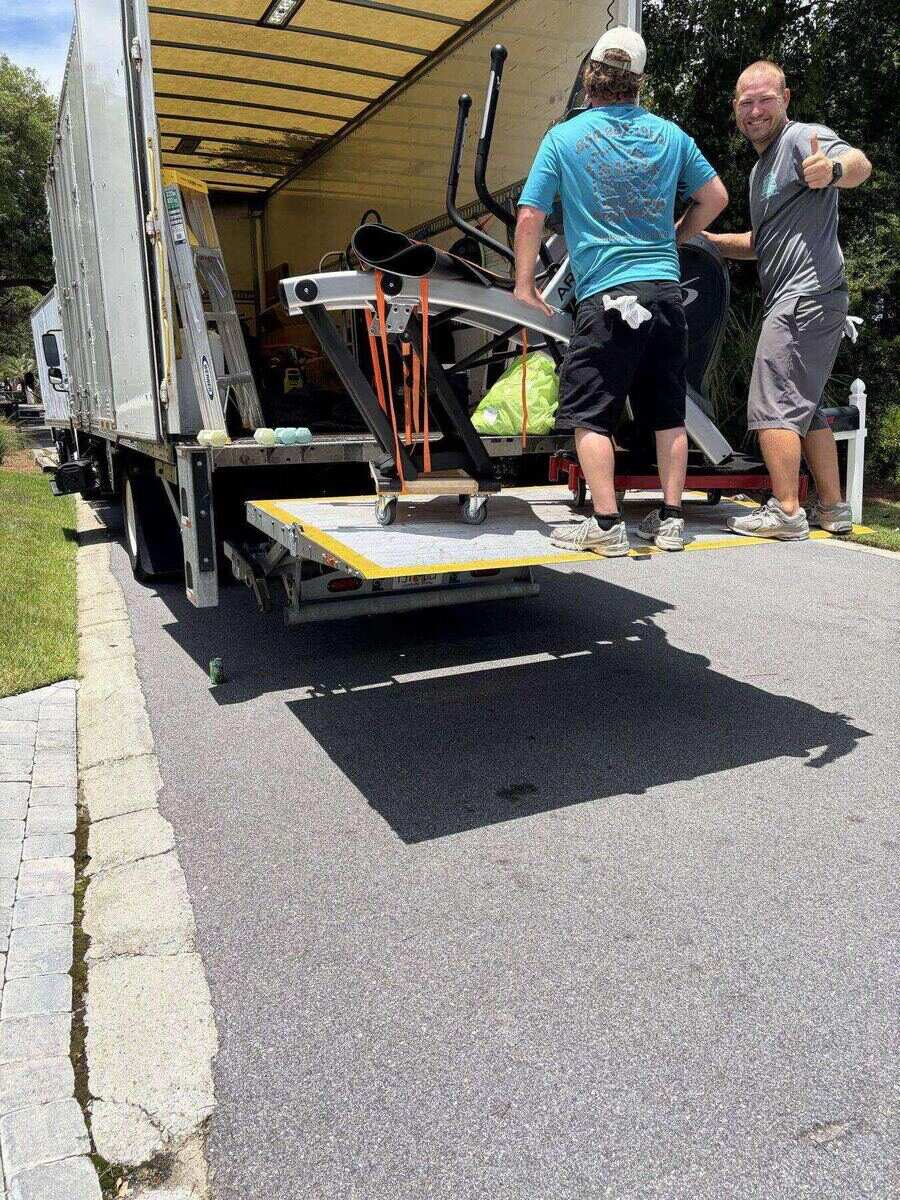Beach House Moving crew loading gym equipment onto a truck liftgate on the Emerald Coast