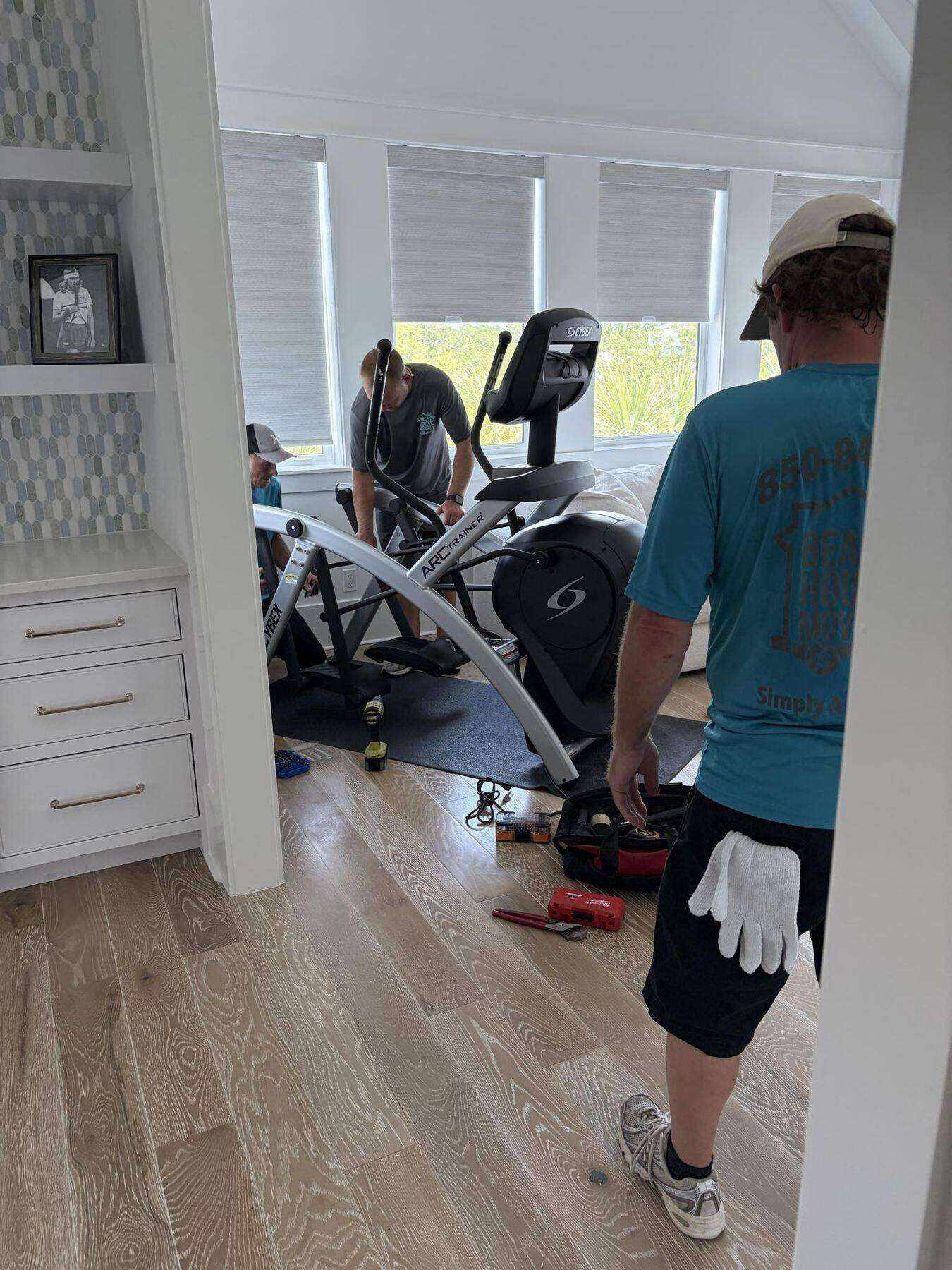 Beach House Moving crew assembling and placing home gym equipment after delivery