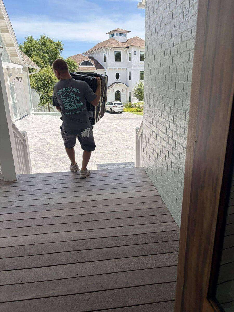 Beach House Moving mover carrying a wrapped item into a luxury beach home